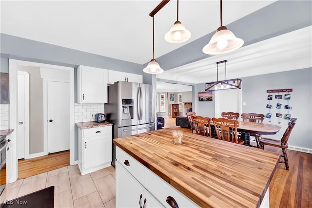 kitchen with hanging light fixtures, backsplash, white cabinetry, and stainless steel fridge with ice dispenser