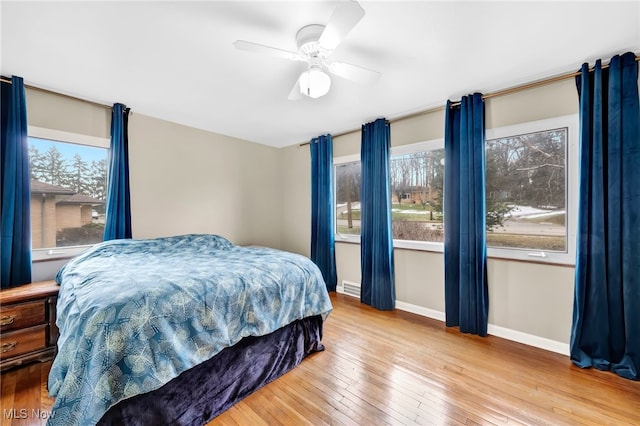 bedroom with a ceiling fan, wood-type flooring, and baseboards