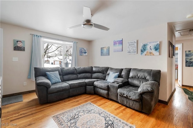 living area featuring light wood finished floors, a ceiling fan, and baseboards