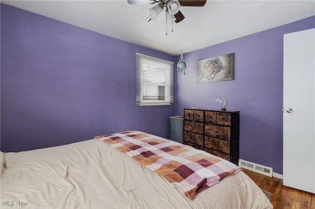 bedroom featuring a ceiling fan, wood finished floors, visible vents, and baseboards