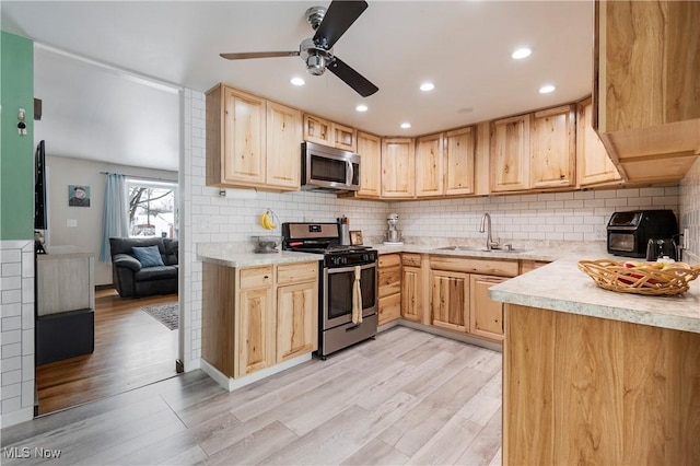 kitchen with appliances with stainless steel finishes, light brown cabinets, a sink, and light wood finished floors