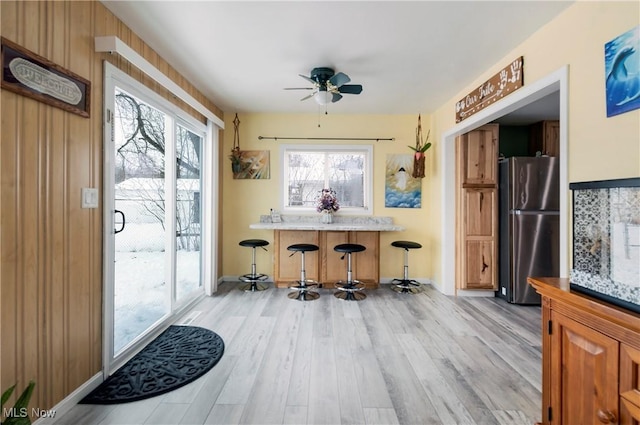 interior space featuring a ceiling fan, light wood-type flooring, and a dry bar