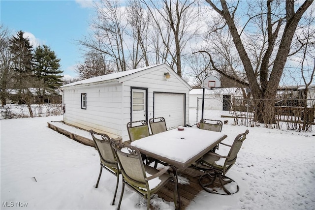 exterior space featuring a garage, outdoor dining area, an outbuilding, and fence