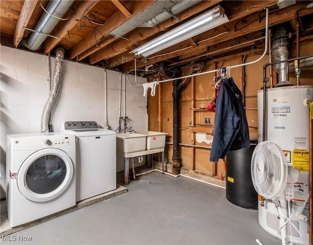 unfinished basement with concrete block wall, water heater, and independent washer and dryer