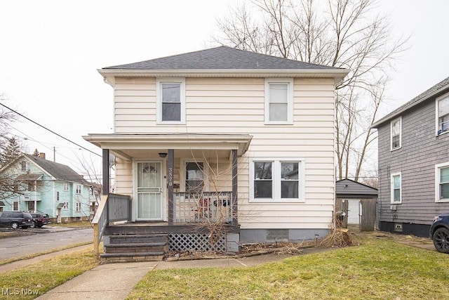 traditional style home featuring a front lawn, covered porch, a shingled roof, and crawl space