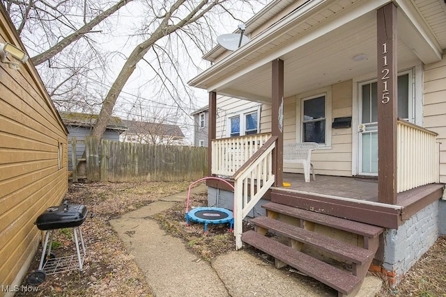 property entrance with covered porch and fence