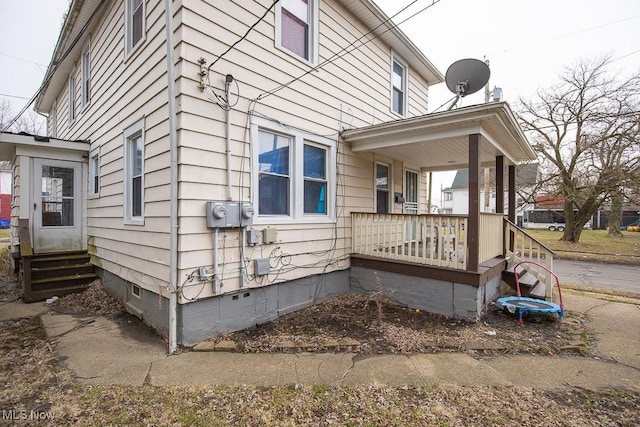 view of side of property featuring covered porch, crawl space, and entry steps