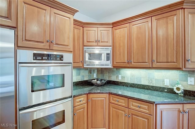 kitchen featuring appliances with stainless steel finishes, dark stone countertops, and tasteful backsplash