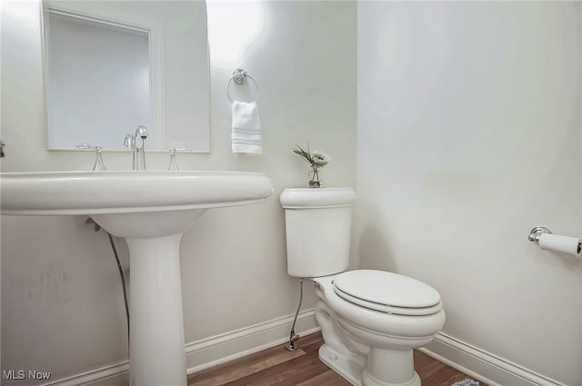 half bathroom featuring baseboards, toilet, and wood finished floors