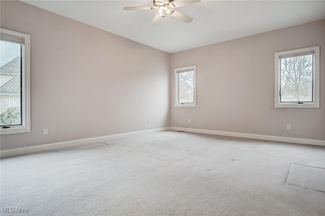 empty room featuring light carpet, vaulted ceiling, a ceiling fan, and baseboards