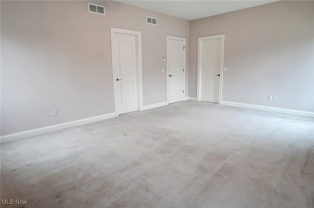 spare room with carpet, baseboards, and visible vents