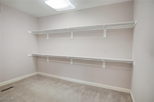 walk in closet with visible vents and light colored carpet