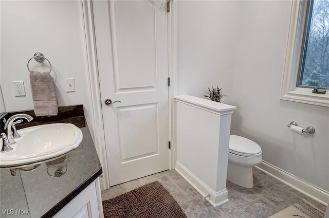 bathroom featuring vanity, toilet, and baseboards