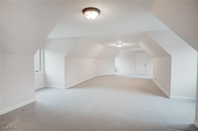 bonus room featuring lofted ceiling, light carpet, and baseboards