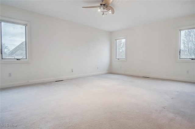 unfurnished room featuring light colored carpet, a healthy amount of sunlight, and baseboards