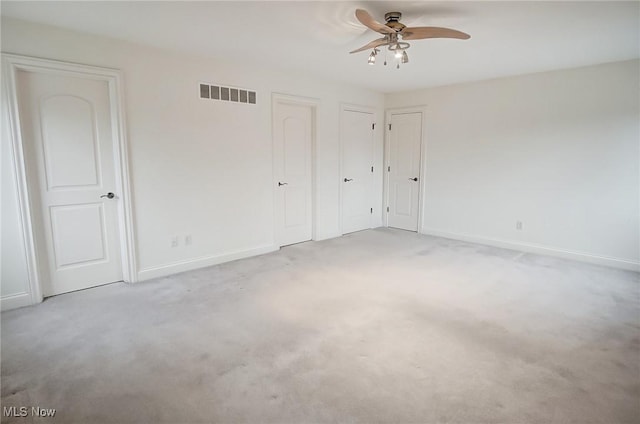 interior space featuring light colored carpet, visible vents, ceiling fan, and baseboards