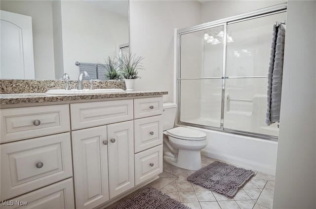 bathroom featuring toilet, tile patterned flooring, bath / shower combo with glass door, and vanity