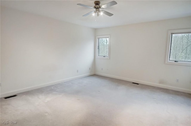 unfurnished room with a ceiling fan, visible vents, and baseboards