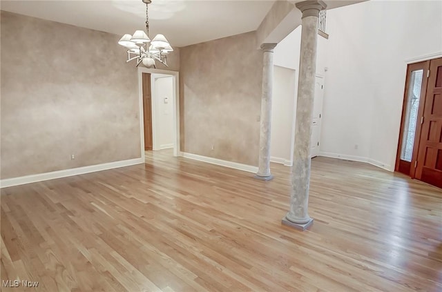 unfurnished dining area featuring light wood-style floors, decorative columns, and baseboards