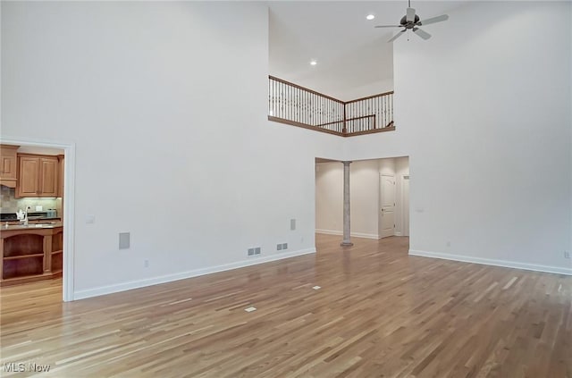 unfurnished living room with visible vents, light wood-type flooring, a ceiling fan, and baseboards