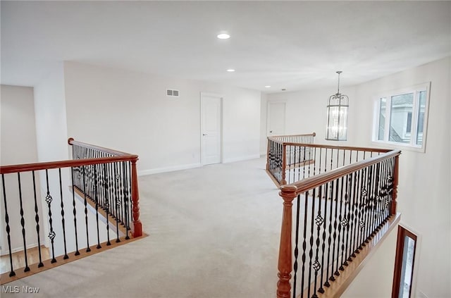 hall with a notable chandelier, recessed lighting, visible vents, carpet flooring, and an upstairs landing