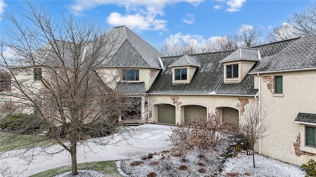 french country inspired facade with concrete driveway and stucco siding