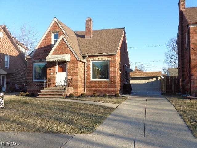 view of front of home with an outbuilding, brick siding, and a chimney