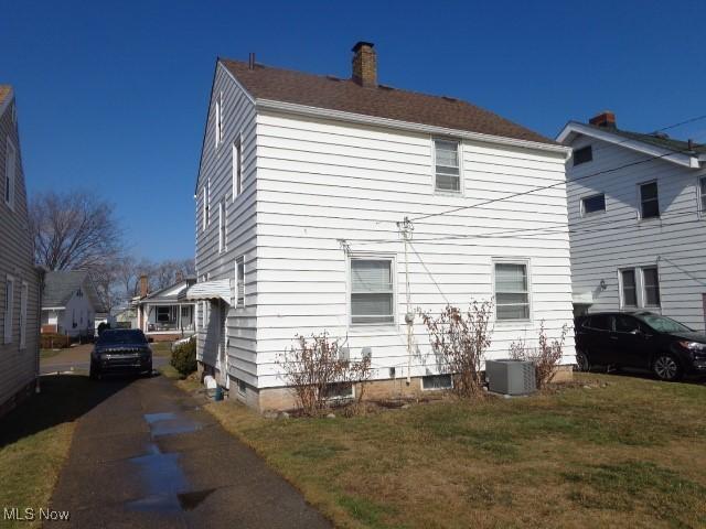 back of house with a yard, a chimney, and central air condition unit