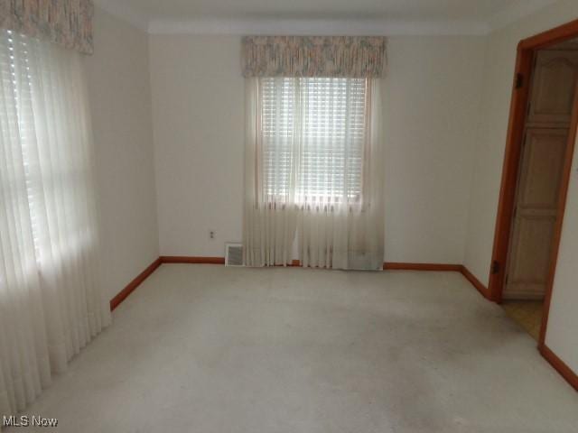 spare room with visible vents, crown molding, light carpet, and baseboards