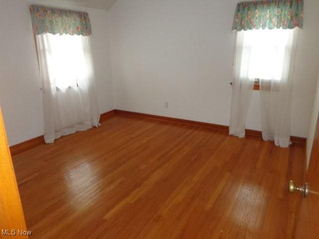 unfurnished room with a wealth of natural light, baseboards, and light wood finished floors