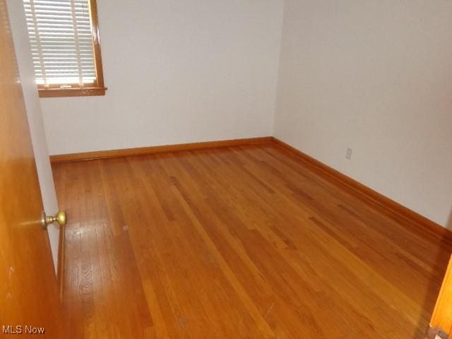 empty room featuring wood finished floors and baseboards