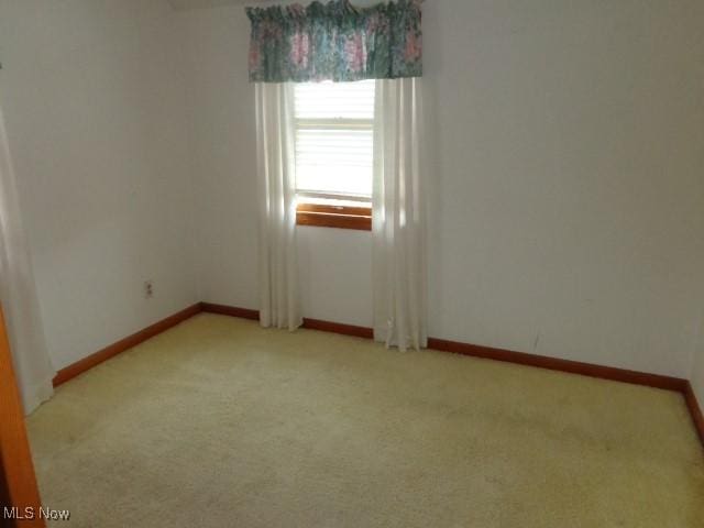 empty room with light colored carpet and baseboards