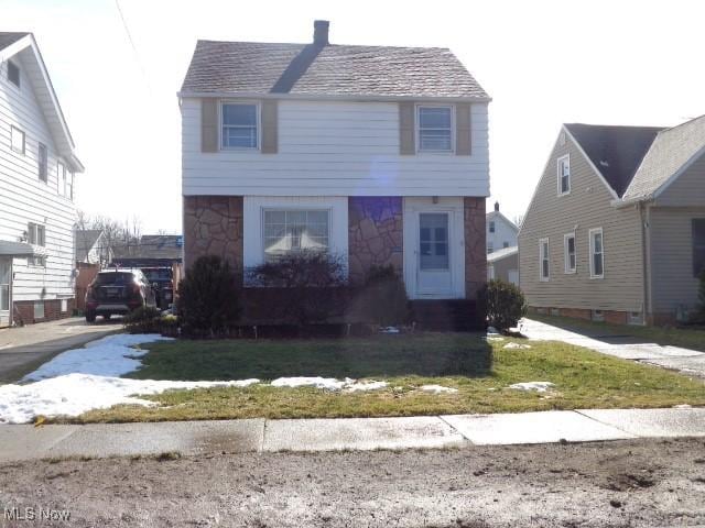 view of front facade featuring stone siding and a front lawn