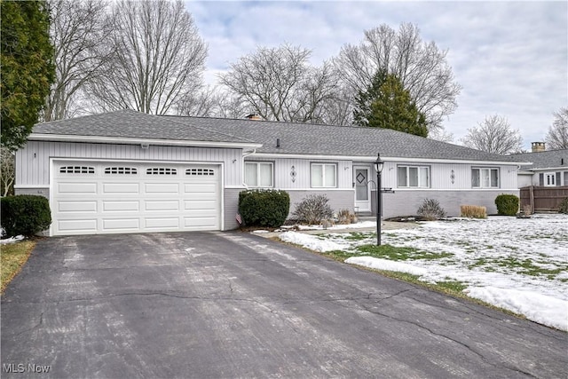 ranch-style house with brick siding, driveway, an attached garage, and roof with shingles