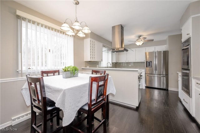 dining space featuring a baseboard radiator, dark wood-style flooring, wainscoting, and ceiling fan with notable chandelier