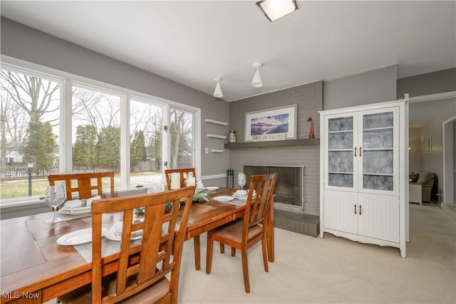 dining space with light colored carpet and a fireplace