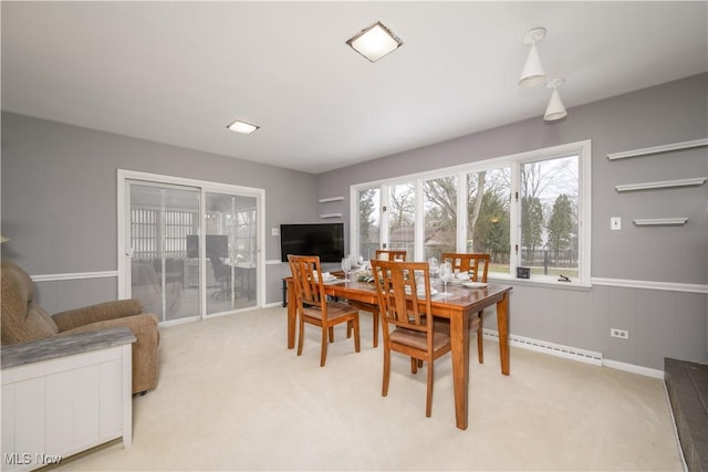 dining area with light carpet, a baseboard heating unit, and wainscoting