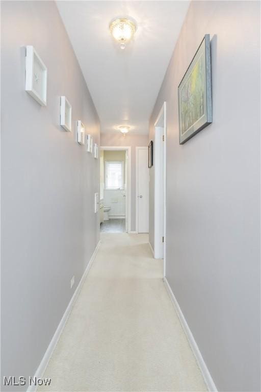 corridor featuring light carpet and baseboards