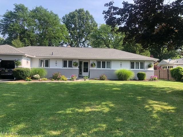 ranch-style home featuring a front lawn, an attached garage, and fence