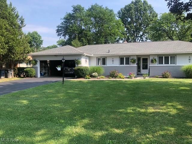 ranch-style house featuring a garage, driveway, and a front lawn