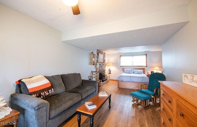 bedroom featuring light wood-type flooring, a brick fireplace, and ceiling fan