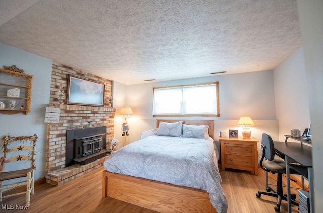 bedroom featuring a textured ceiling, visible vents, and wood finished floors