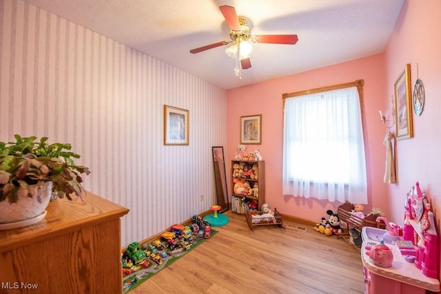 game room with wallpapered walls, visible vents, baseboards, a ceiling fan, and wood finished floors