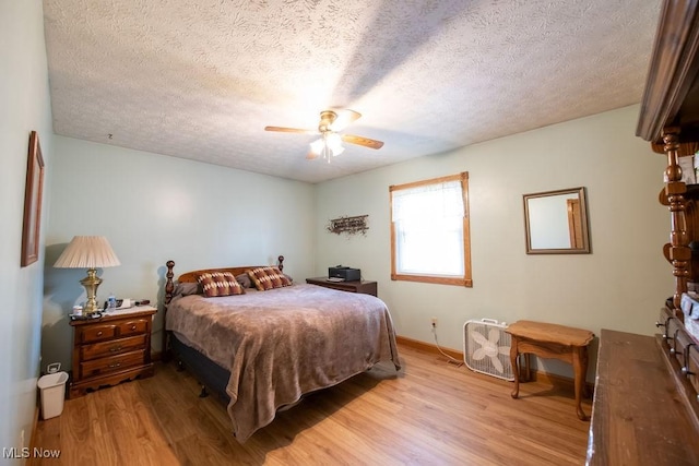 bedroom with light wood finished floors, a ceiling fan, and a textured ceiling