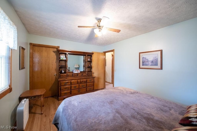 bedroom featuring a ceiling fan, a textured ceiling, and wood finished floors