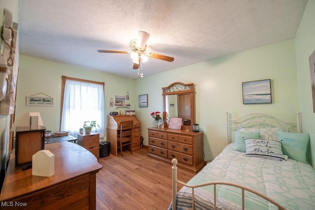 bedroom featuring a ceiling fan, light wood-style flooring, and a textured ceiling