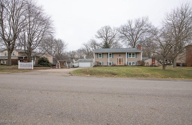 raised ranch featuring a front yard, an outdoor structure, and a chimney