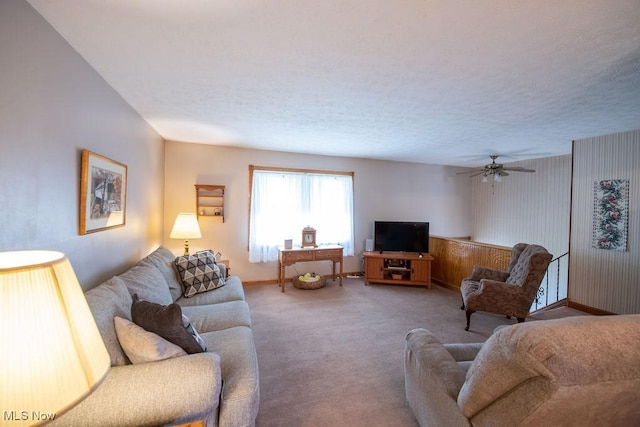 carpeted living area featuring a textured ceiling, a ceiling fan, and baseboards