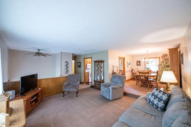 living room with ceiling fan with notable chandelier, light carpet, and wallpapered walls