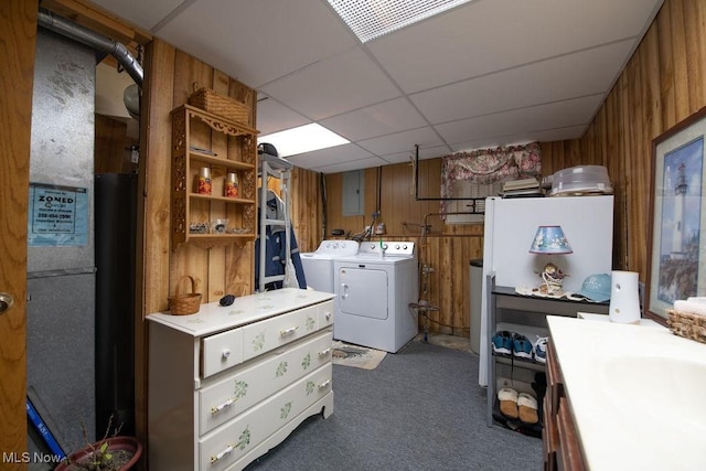 clothes washing area with carpet floors, washing machine and dryer, laundry area, and wood walls